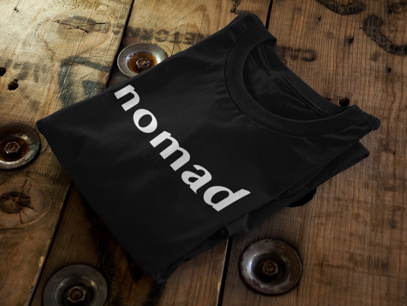 May include: Black t-shirt with the word "nomad" printed in white on the front.