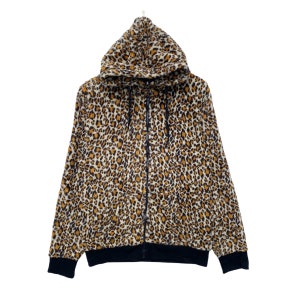 Peut inclure: Un sweat à capuche zippé en polaire à imprimé léopard marron et noir avec une capuche noire et des poignets et une ourlet côtelés noirs.