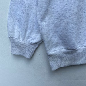 May include: Close-up of the gray ribbed cuffs of a sweatshirt. The cuffs are made of a soft, comfortable fabric.
