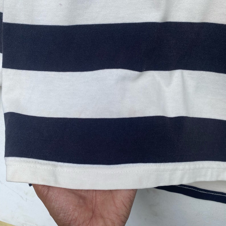 May include: A white and navy blue striped long-sleeve shirt with a ribbed knit texture.