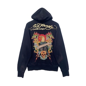 May include: Black zip-up hoodie with a large graphic print on the back. The graphic features a skull, eagle, and dragons with the text "Ed Hardy" and "By Christian Audigier".