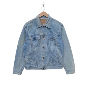 May include: A light blue denim jacket with a button closure and two front pockets. The jacket has a brand label that reads "Edwin" on the left side of the chest.
