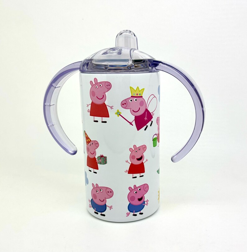 Pode incluir: Um copo de a&ccedil;o inoxid&aacute;vel branco com tampa e al&ccedil;as roxas. O copo apresenta um padr&atilde;o repetido de personagens do Peppa Pig em v&aacute;rias poses.
