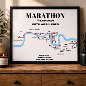 Op de afbeelding: Een ingelijste print met het woord "MARATHON" bovenaan, en "LONDON" met de datum "26 APRIL 2026" eronder. De print toont een kaart van de marathonroute met de naam, het startnummer en de chip tijd van de loper.