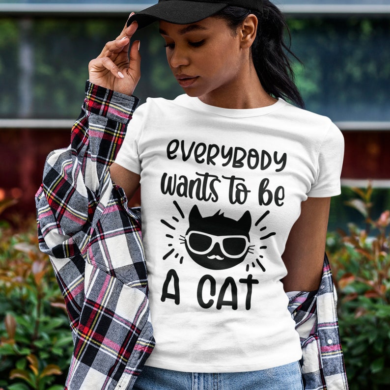 May include: White t-shirt with black text that reads "Everybody wants to be a cat" and a black cat wearing sunglasses graphic.