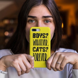May include: A yellow phone case with black text that reads "Boys? Whatever. Cats? Forever."