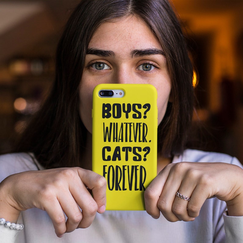 May include: A yellow phone case with black text that reads "Boys? Whatever. Cats? Forever."