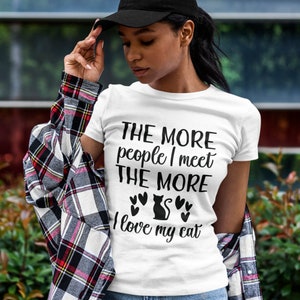 May include: White t-shirt with black text that reads "The more people I meet the more I love my cat" with a black cat silhouette and hearts.
