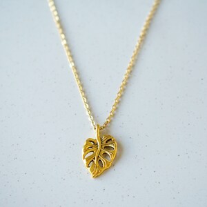 Peut inclure: Un collier en or avec un pendentif en forme de feuille d&eacute;coup&eacute;e. La feuille est un design simple et stylis&eacute;.