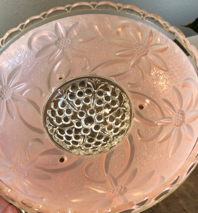 Puede incluir: Una l&aacute;mpara de techo de cristal rosa con un dise&ntilde;o floral y un centro de cristal transparente.