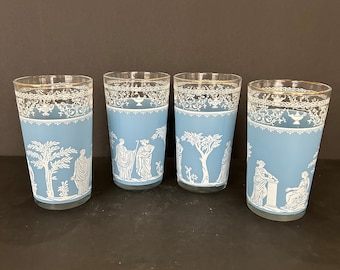 Può includere: Set di quattro bicchieri blu in vetro con disegni bianchi di ispirazione greca. Ogni bicchiere presenta una scena diversa con figure e alberi.