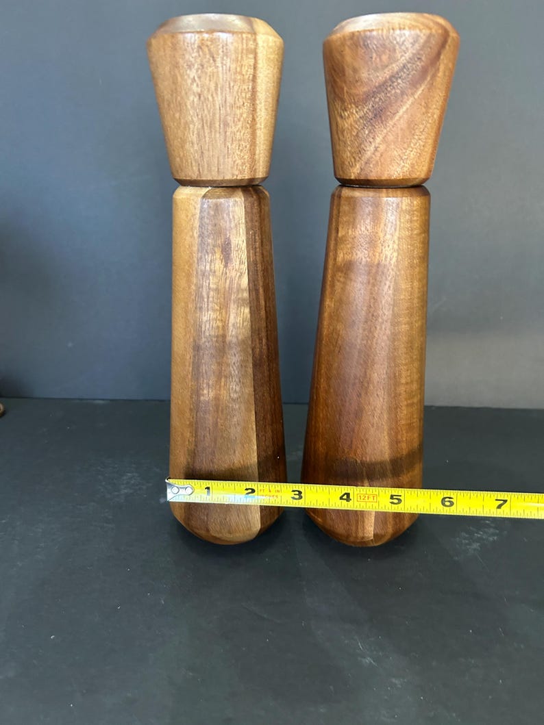 Pu&ograve; includere: Un set di due saliere e pepiere in legno con venature di legno marrone scuro. I salieri sono alti circa 15 cm.
