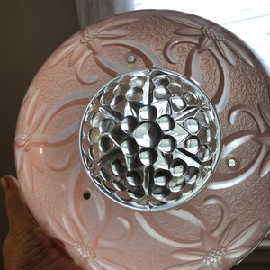 Puede incluir: Una l&aacute;mpara de techo de cristal rosa con un dise&ntilde;o floral y un centro de cristal transparente con textura de burbujas.
