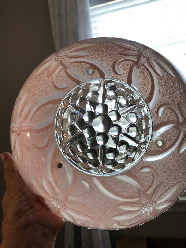 Puede incluir: Una l&aacute;mpara de techo de cristal rosa con un dise&ntilde;o floral y un centro de cristal transparente con textura de burbujas.