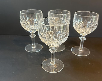 Könnte beinhalten: Vier klare Kristall-Weingläser mit geschliffenem Design. Die Gläser haben eine abgerundete Schale, einen schlanken Stiel und einen kreisförmigen Fuß. Die Gläser sind auf einer dunklen Oberfläche angeordnet.
