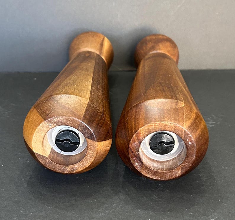 Pu&ograve; includere: Due macinini per sale e pepe in legno con finitura in legno marrone scuro. I macinini hanno una forma cilindrica con una parte superiore e inferiore leggermente rastremata. La parte inferiore di ogni macinino ha un meccanismo di macinazione in plastica nera.