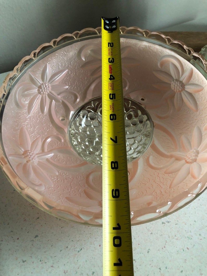 Puede incluir: Una l&aacute;mpara de techo de cristal rosa con un dise&ntilde;o floral y una pieza central de cristal transparente. La l&aacute;mpara tiene un di&aacute;metro de 25,4 cm.