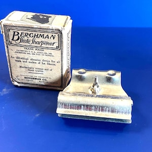 May include: Vintage Berghman Skate Sharpener with original box. The box is beige with black text and a graphic of a skate. The metal sharpener is silver. The box reads "An individual abrasive device for all types and makes of Ice Skates."