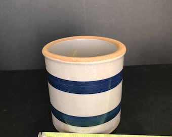 Puede incluir: Un tarro de cerámica blanco con rayas azules. El tarro mide aproximadamente 15 cm de alto.