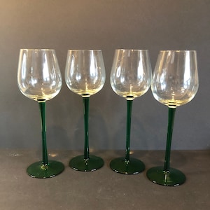 Op de afbeelding: Set van vier heldere glazen wijnglazen met groene stelen en voetjes.