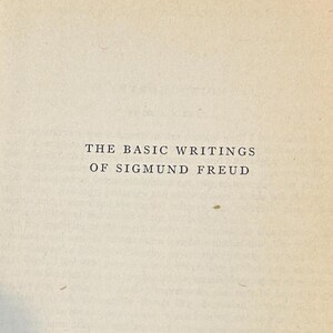 Peut inclure: Gros plan sur une page de livre avec le titre "THE BASIC WRITINGS OF SIGMUND FREUD" imprim&eacute; en noir. Le papier est de couleur cr&egrave;me, l&eacute;g&egrave;rement vieilli.