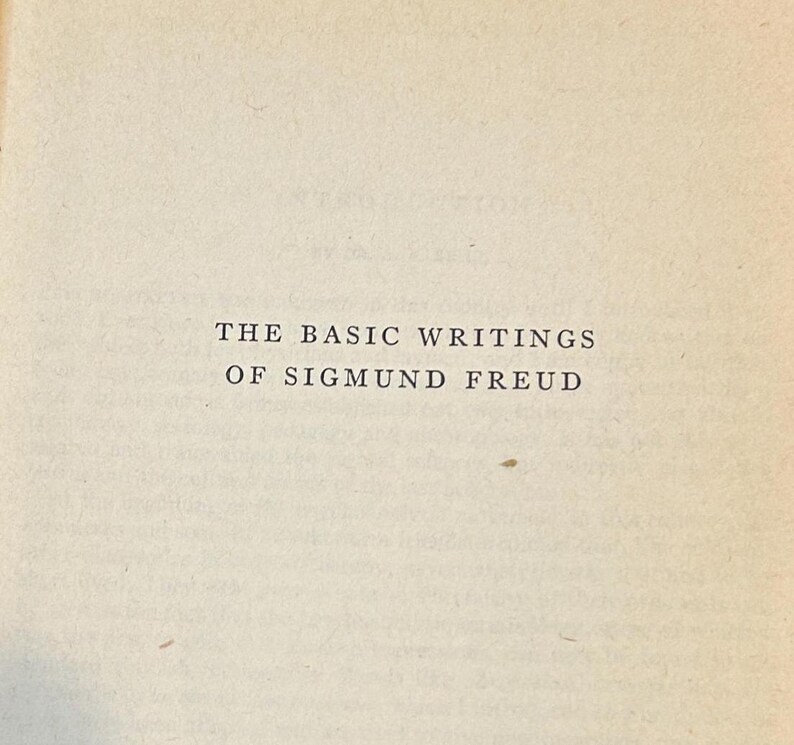 Peut inclure: Gros plan sur une page de livre avec le titre "THE BASIC WRITINGS OF SIGMUND FREUD" imprim&eacute; en noir. Le papier est de couleur cr&egrave;me, l&eacute;g&egrave;rement vieilli.