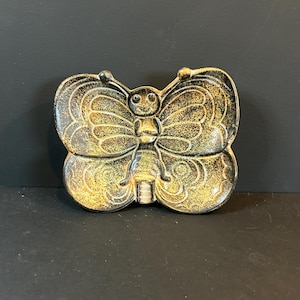 以下が含まれることがあります： 蝶の形をした装飾的な小物入れ。 黒を基調とし、金色のアクセントが施された、詳細な蝶のデザインが特徴です。 セラミックまたは同様の素材で作られています。