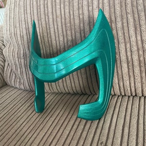 May include: A teal green plastic helmet with a curved design. The helmet is made of a smooth, shiny plastic.