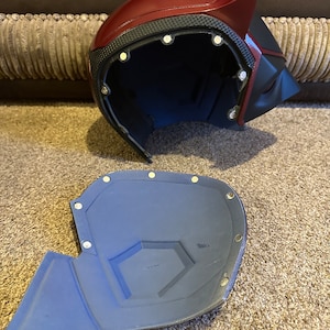 以下が含まれることがあります： 赤と黒のプラスチック製のヘルメットで、青いフォームの裏地が付いています。ヘルメットは2つの部分に分かれており、スーパーヒーローのヘルメットのように見えるように設計されています。