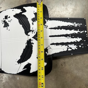 May include: Black and white car floor mat with a world map design. The mat is approximately 13 inches long. The design features white continents on a black background, with a textured surface.