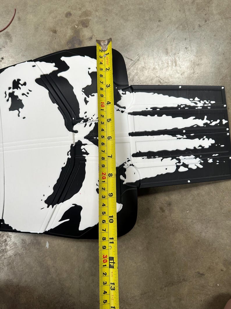 May include: Black and white car floor mat with a world map design. The mat is approximately 13 inches long. The design features white continents on a black background, with a textured surface.