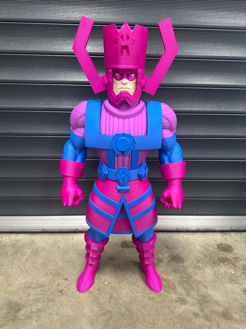 May include: A large, colorful action figure of Galactus, a comic book character. The figure is predominantly pink and blue, with a detailed helmet and armor. The figure stands on a concrete surface against a dark gray background.