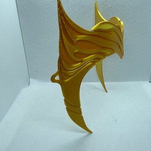 May include: A gold-coloured, 3D printed crown with a decorative, intricate design. The crown is made of plastic and has a smooth, shiny finish.