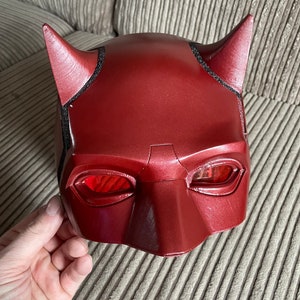 May include: Red plastic Daredevil mask with black detailing around the eyes and horns. The mask has a red, translucent visor.