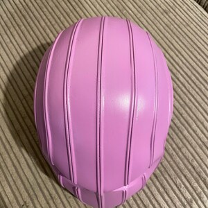 May include: A pink ceramic bowl with a ribbed design. The bowl is round and has a smooth, glossy finish.