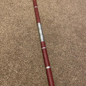 May include: A red and silver telescopic staff with a textured grip.