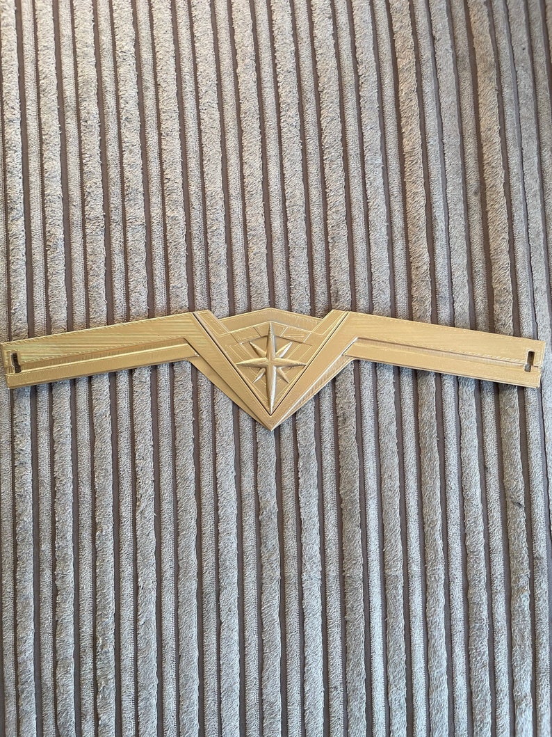 May include: A gold-coloured plastic headband with a star-shaped design in the centre. The headband is shaped like a crown.