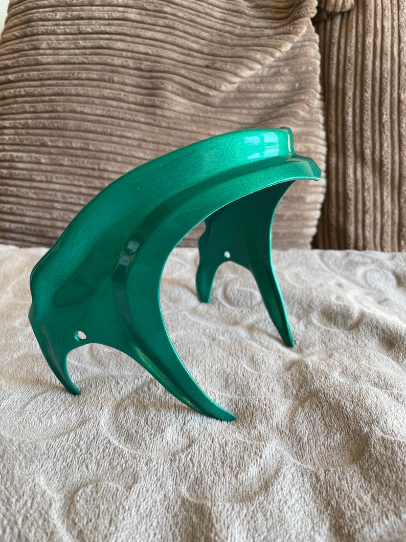 K&ouml;nnte beinhalten: Eine gr&uuml;ne Motorrad-Scheinwerferverkleidung aus Kunststoff. Die Verkleidung ist gebogen und hat eine glatte, gl&auml;nzende Oberfl&auml;che.