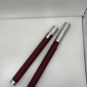 May include: Two silver and burgundy colored nunchucks with a textured grip.