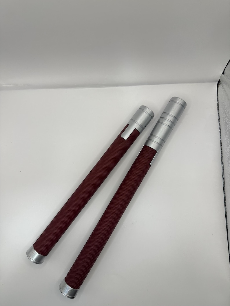 May include: Two silver and burgundy colored nunchucks with a textured grip.