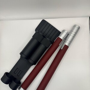 May include: A black carrying case with two red and silver telescopic batons. The batons have a textured grip.