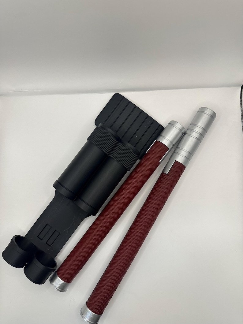 May include: A black carrying case with two red and silver telescopic batons. The batons have a textured grip.