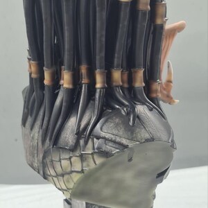 Puede incluir: Busto detallado de un alien&iacute;gena Predator, con un acabado met&aacute;lico texturizado. La escultura presenta las distintivas rastas del Predator, con acentos de color bronce. La base tiene un dise&ntilde;o geom&eacute;trico texturizado, que se suma a la est&eacute;tica de ciencia ficci&oacute;n.