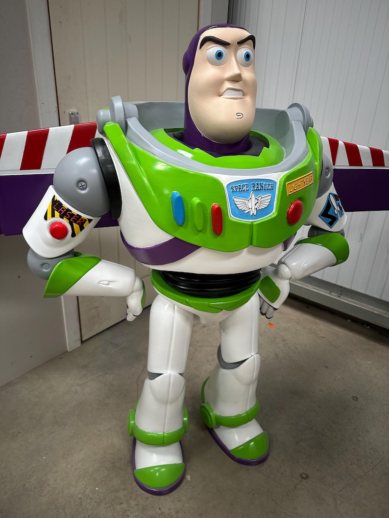 May include: A large Buzz Lightyear figure, featuring a white, green, and purple spacesuit. The figure has a light-skinned face with blue eyes and a determined expression. The chest displays a Space Ranger badge and the word "LIGHTYEAR".