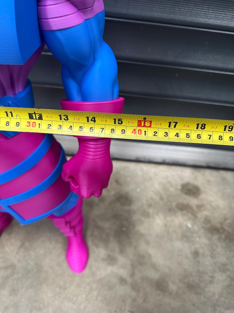 May include: A large, detailed figurine of a comic book character, predominantly blue and magenta. The figure's arm measures approximately 16 inches. The figure has a muscular build and is wearing a costume with blue accents.
