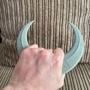 May include: A pair of gray crescent-shaped hand grippers with the text "Grip Strength" printed on them.
