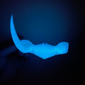 May include: A blue plastic glow-in-the-dark toy shaped like a crescent moon with a pointed tip.