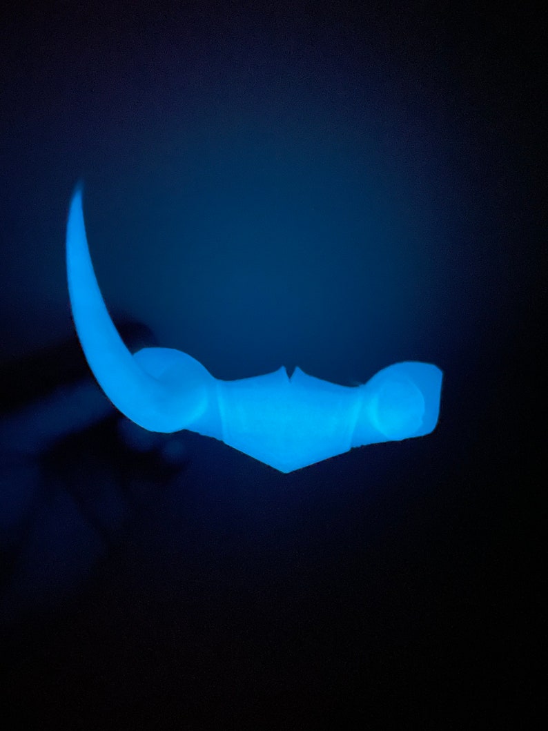 May include: A blue plastic glow-in-the-dark toy shaped like a crescent moon with a pointed tip.