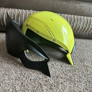 Pode incluir: Uma m&aacute;scara de fantasia de pl&aacute;stico amarela e preta. A m&aacute;scara &eacute; um capacete com uma viseira preta e uma m&aacute;scara preta separada com um queixo pontudo.