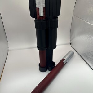 May include: Two silver and maroon retractable batons with a black carrying case. The batons have a textured surface and a silver tip.
